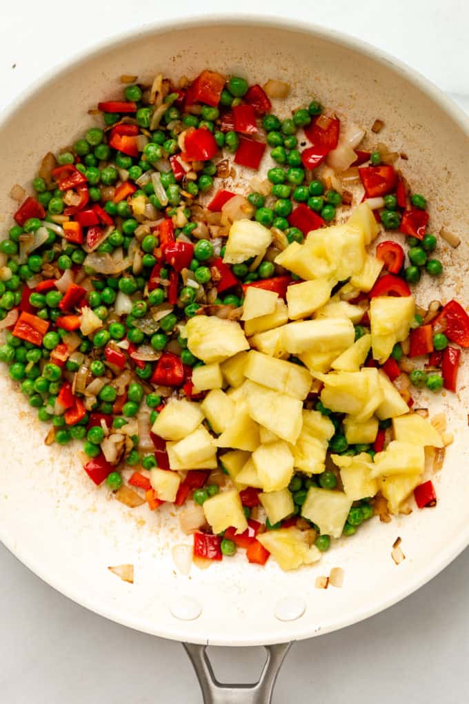 peas, red peppers and pineapple in a white pan