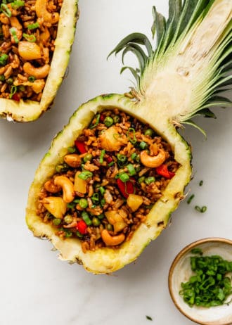 Thai pineapple fried rice in a pineapple bowl with green onions on top