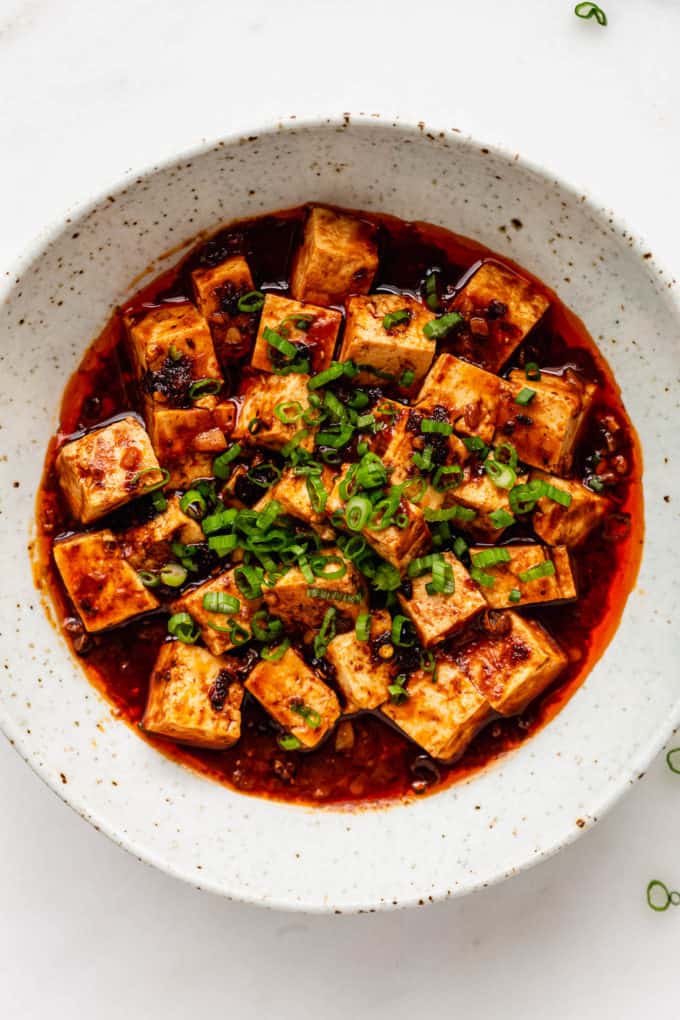mapo tofu in a white speckled bowl topped with scallions