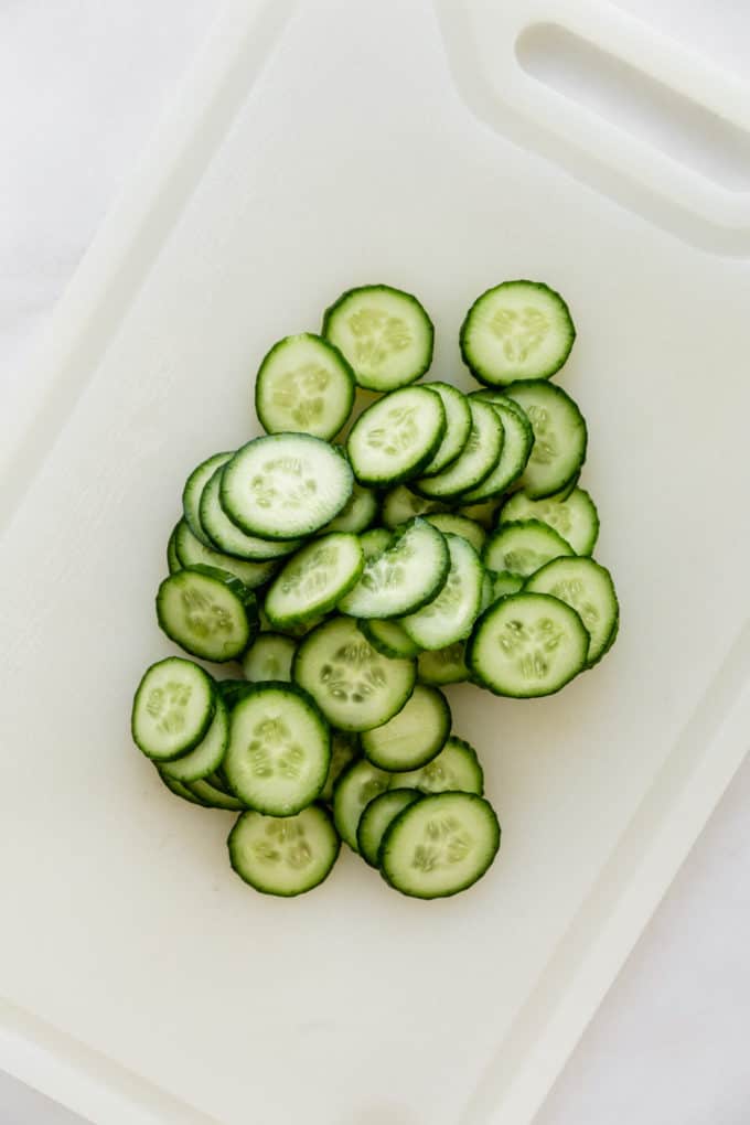 sliced cucumbers on a white cutting board