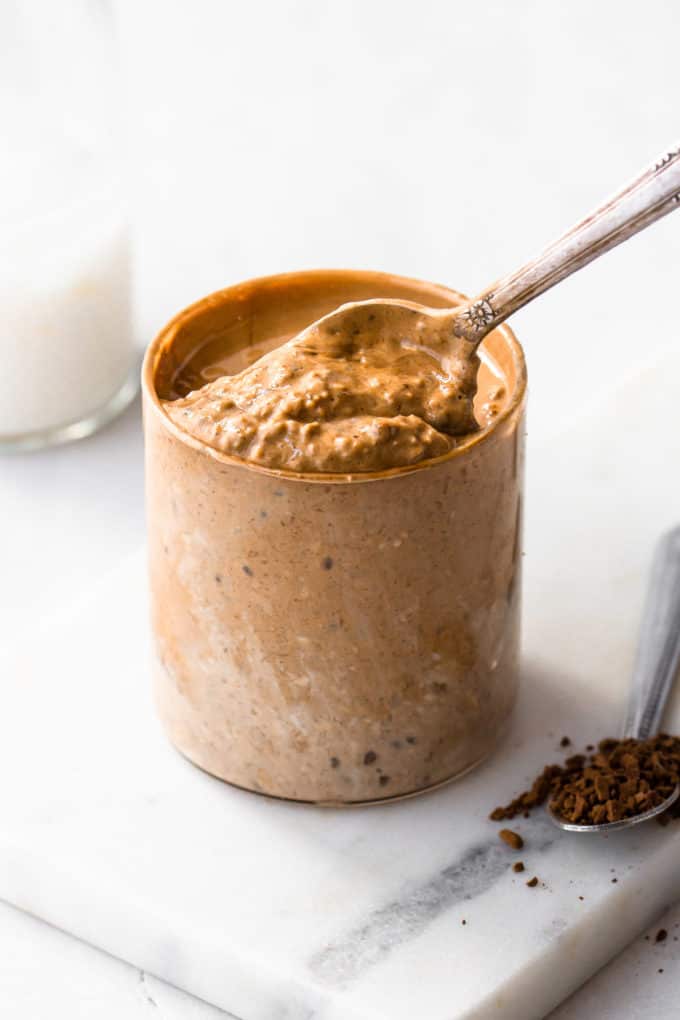 a spoon scooping coffee overnight oats out of a cup