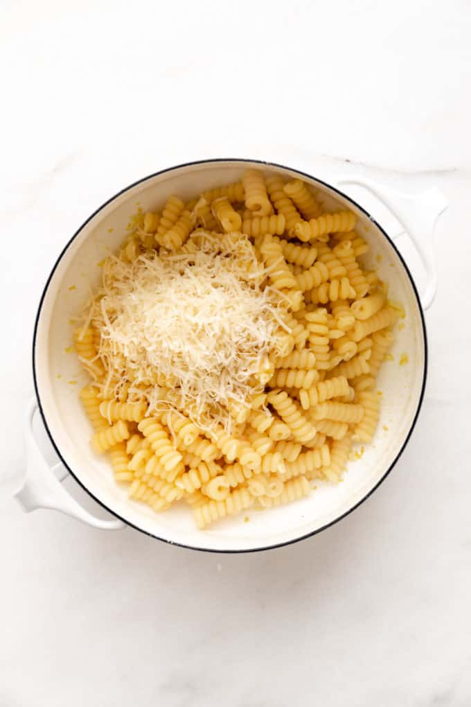 fusilli noodles and grated parmesan cheese in a white pot