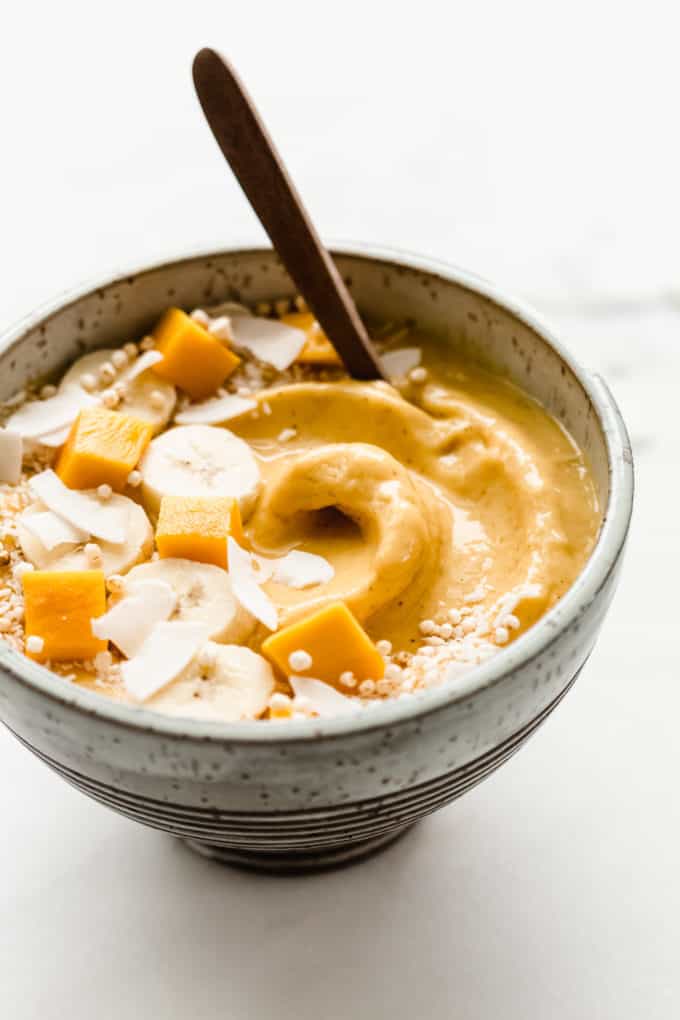 A mango smoothie bowl topped with mango, banana and coconut