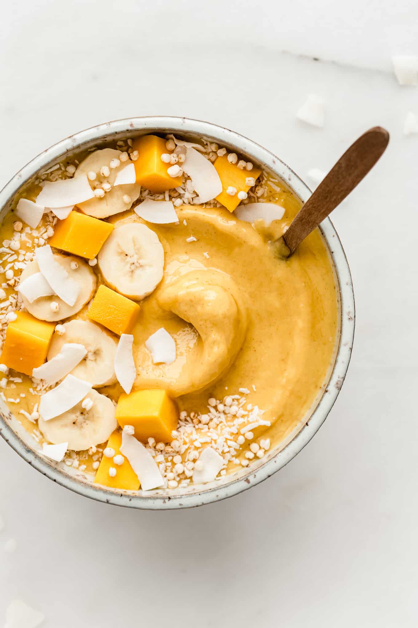 A mango smoothie bowl topped with fruits and coconut flakes