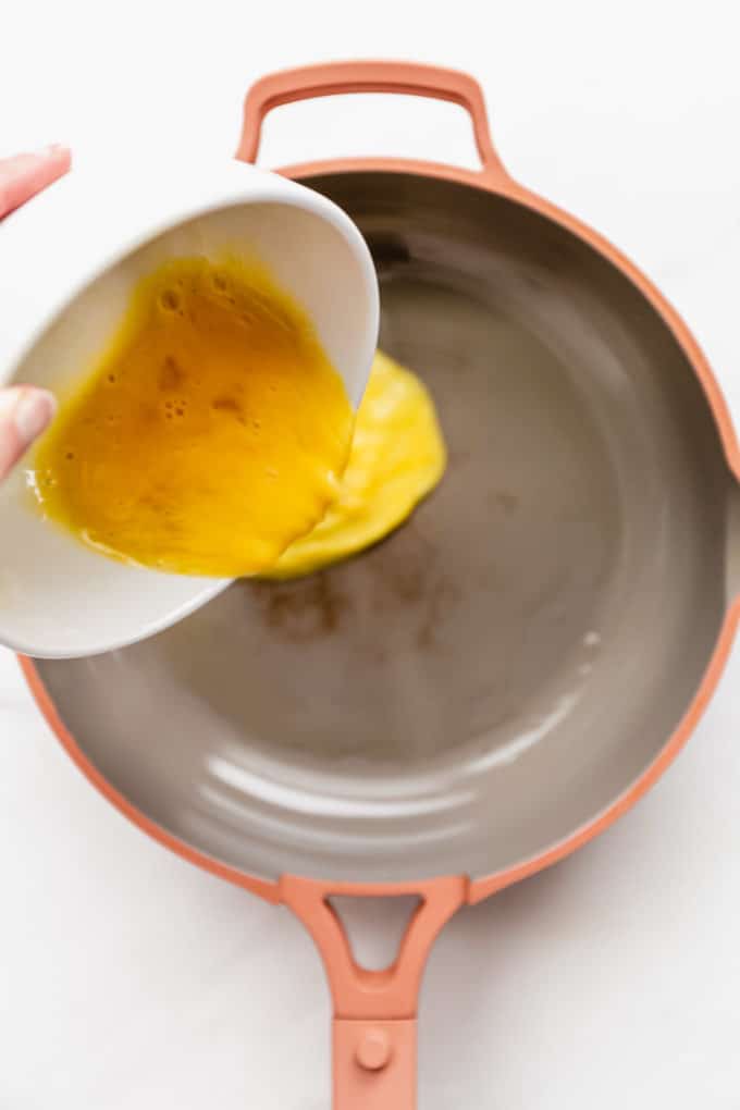 eggs being poured into a pink pan