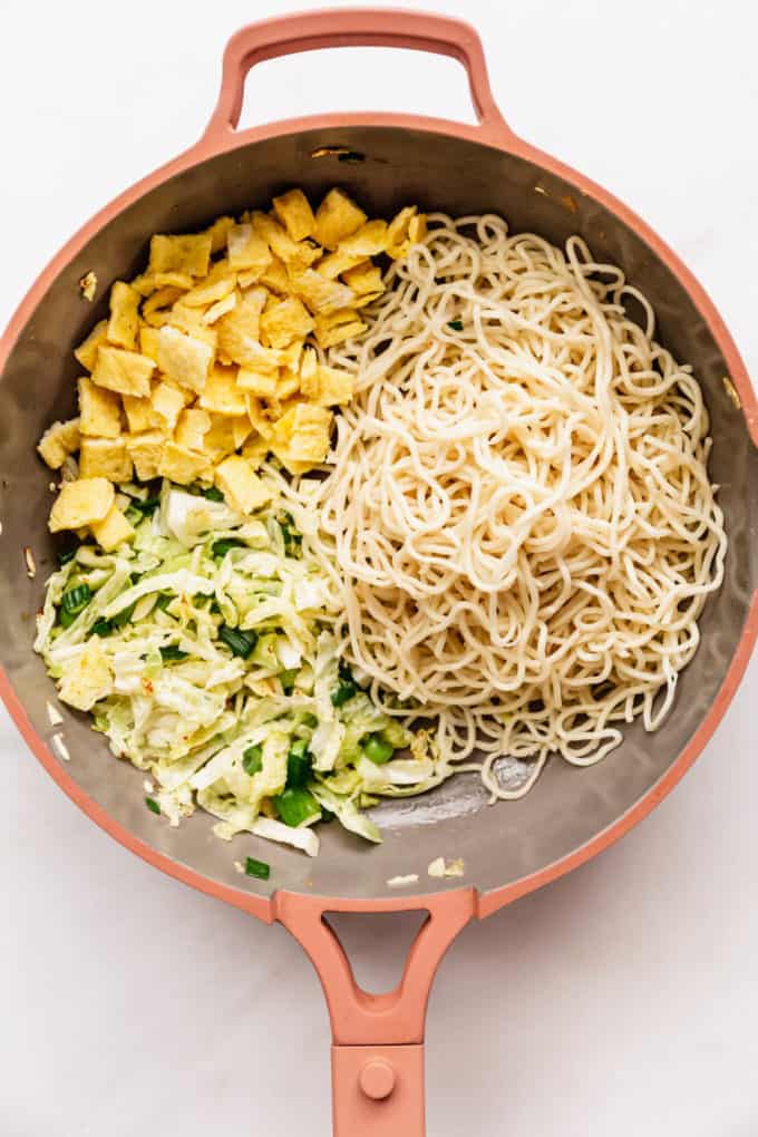 sauteéd vegetables, noodles and omelette in a pink pan