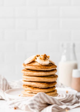 a stack of oat flour pancakes on a white plate on a striped napkin