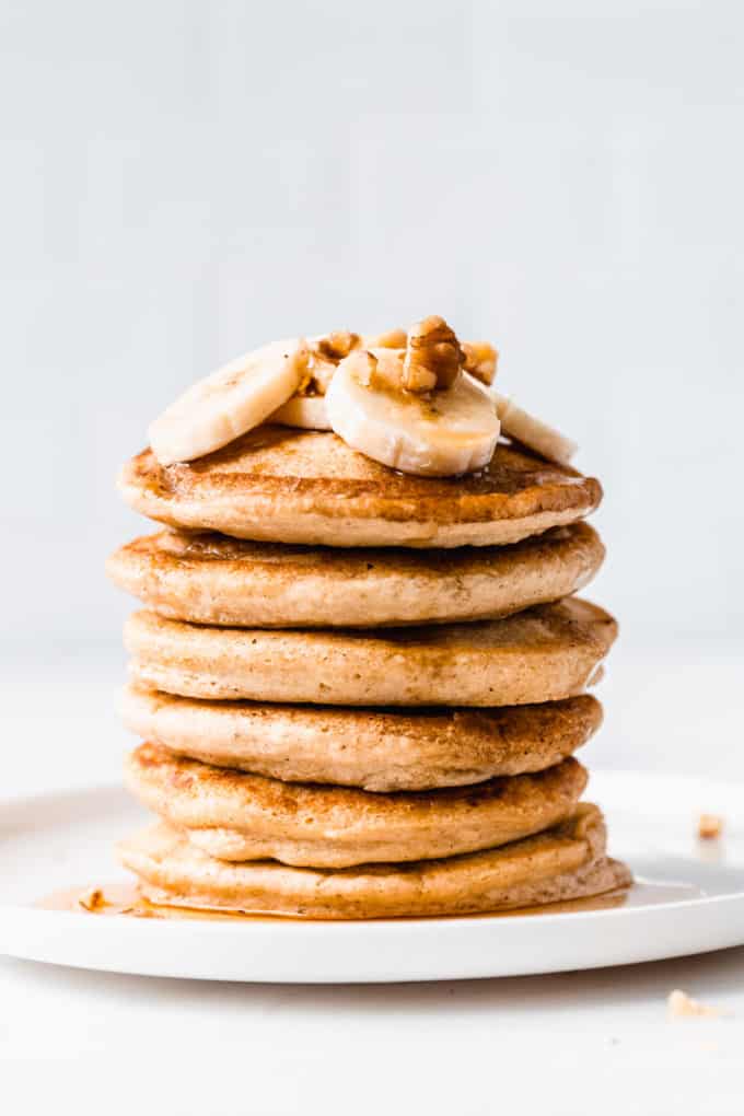 a stack of 6 oat flour pancakes with bananas and walnuts on top