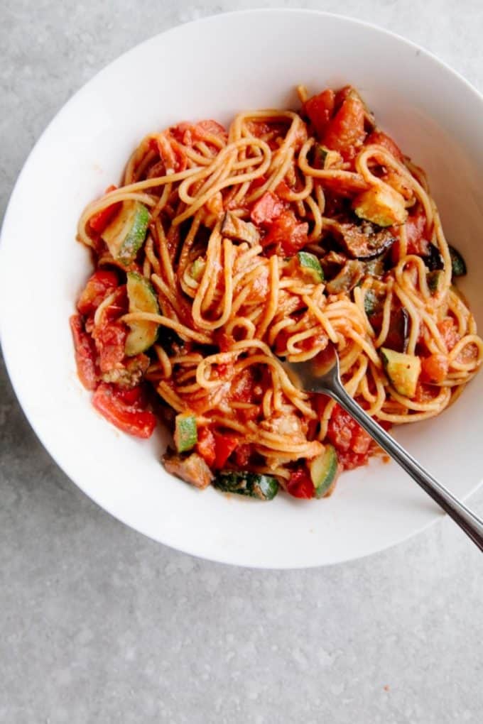 Spaghetti with tomato sauce and veggies in a white bowl
