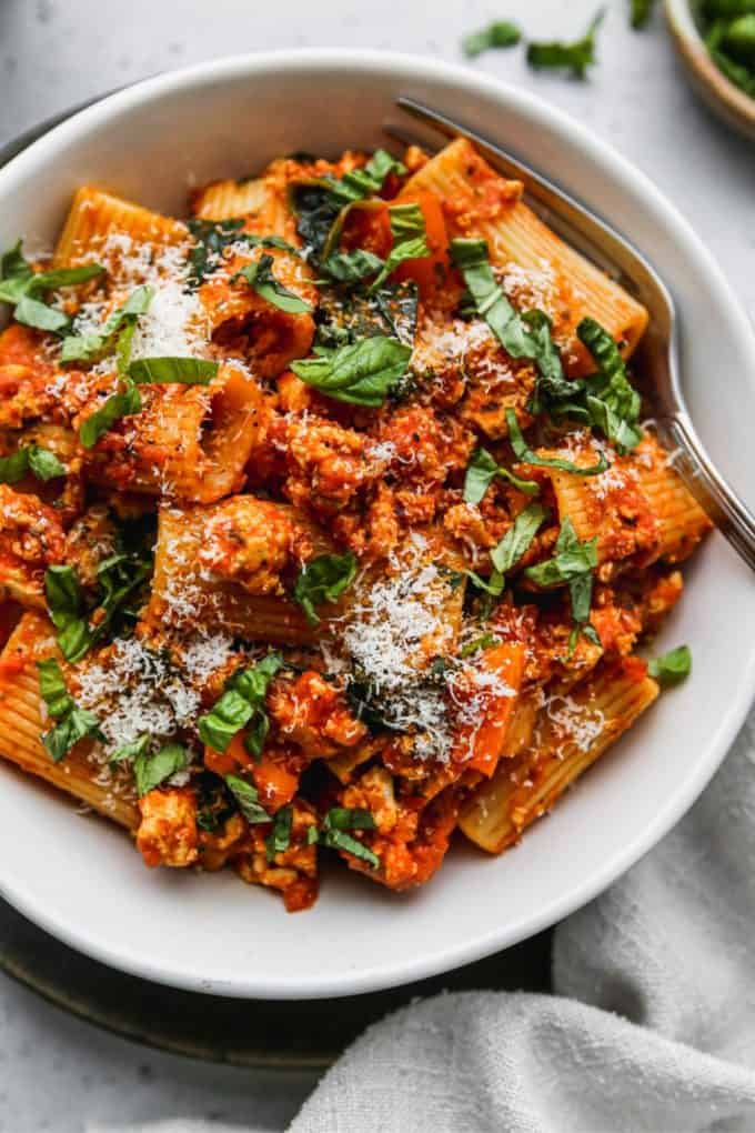 Rigatoni with crumbled tofu and tomato sauce in a white bowl