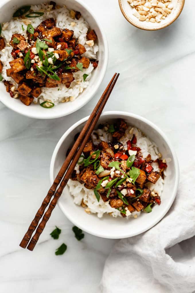 two bowls of kung pao tofu on rice with wood chopsticks