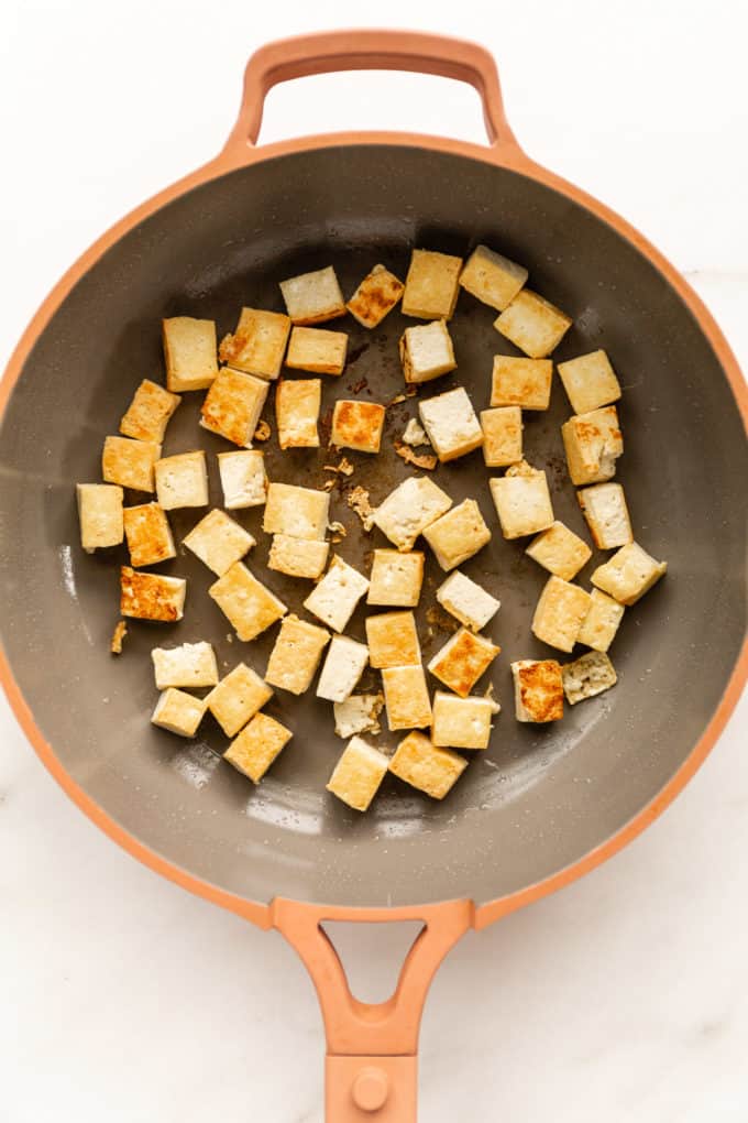 pan-fried cubes of tofu in a pink pan