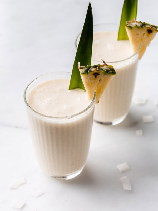 two glases of pina colada smoothies wit a pineapple in them