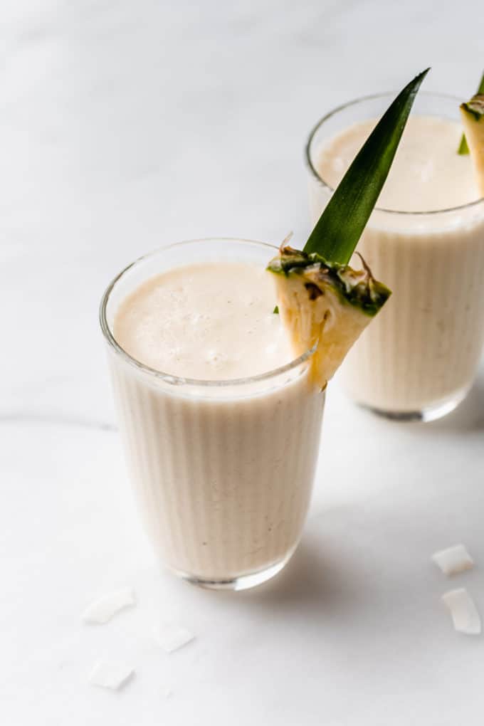 a pina colada smoothie in a glass with a slice of pineapple
