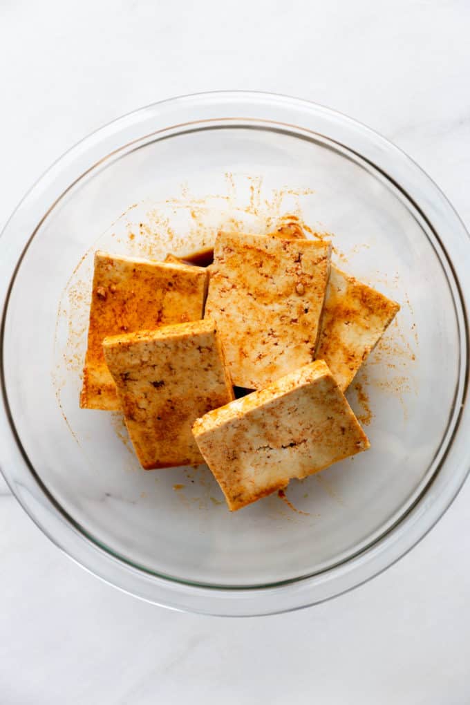 squares of tofu in a clear bowl with marinade