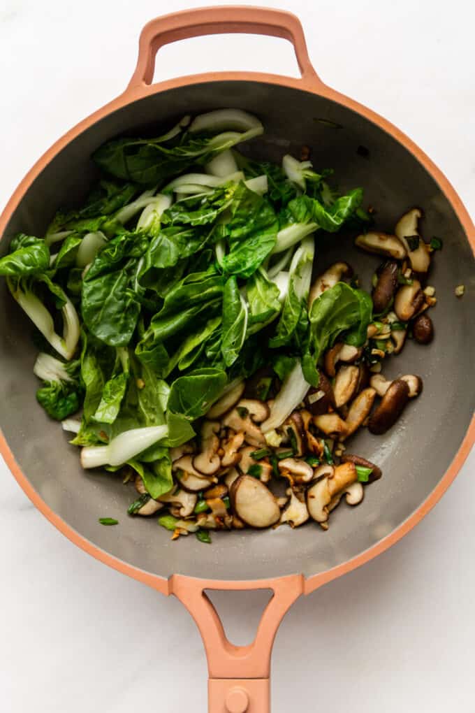 mushrooms and bok choy in a pink pan