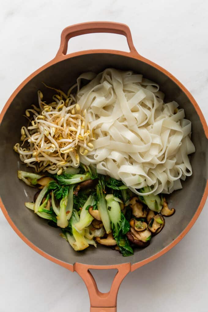 vegetables and rice noodles in a pink pan