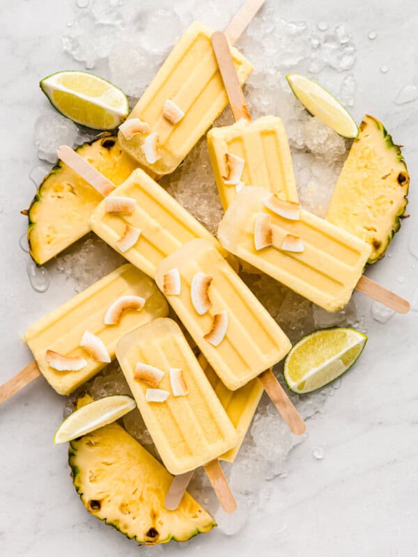 pina colada popsicles on a marble counter topped with coconut flakes