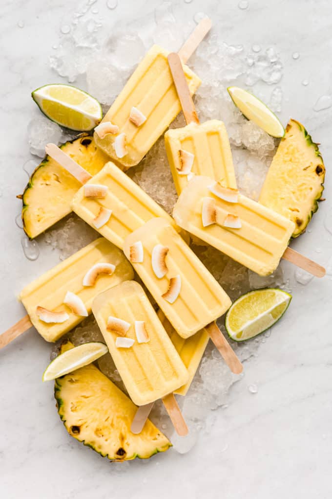 pina colada popsicles on a marble counter topped with coconut flakes