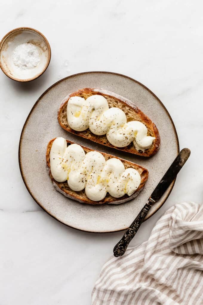 two slices of toast topped with whipped ricotta on a plate