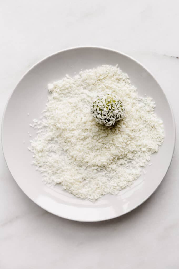 a matcha energy ball in a plate of shredded coconut
