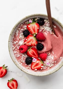 A strawberry smoothie bowl topped with strawberries and shredded coconut