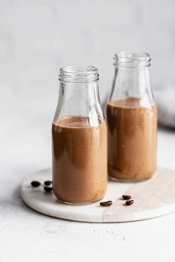two jars of coffee smoothies with coffee beans on the side