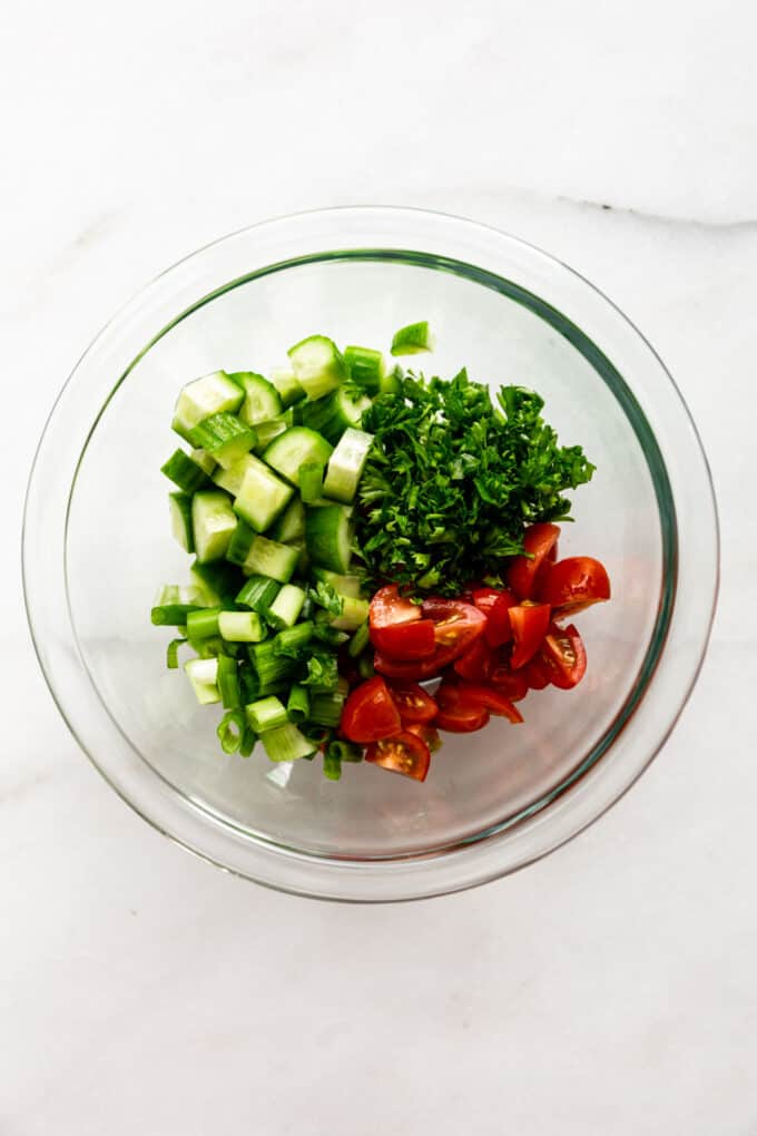 cucumber, parsley and tomatoes in a clear bowl