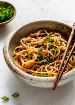 A bowl of garlic noodles topped with green onions