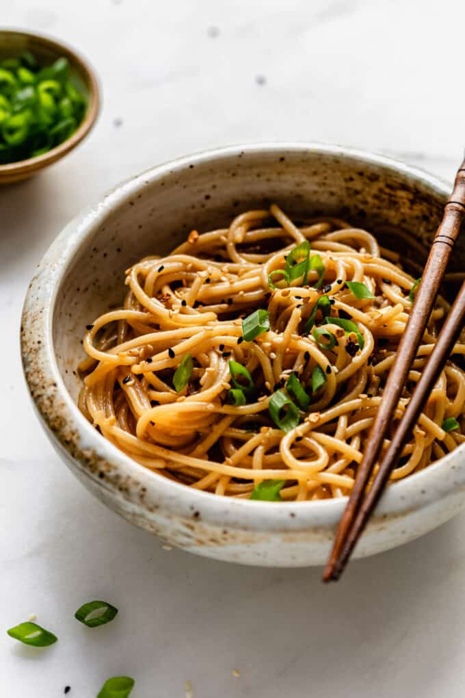A bowl of garlic noodles topped with green onions