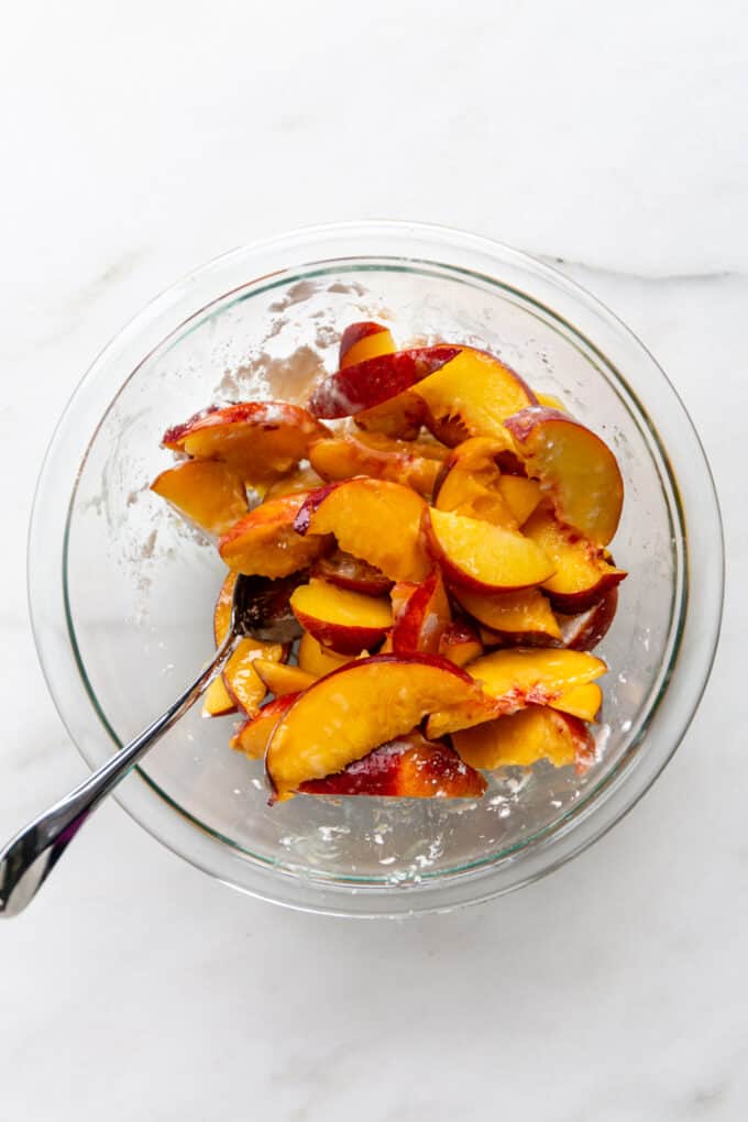 peaches tossed with cornstarch in a clear bowl