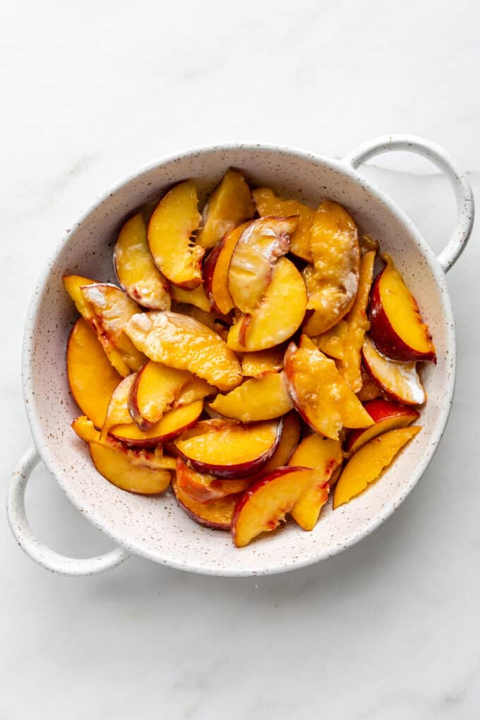 peaches coated with cornstarch in a white baking dish