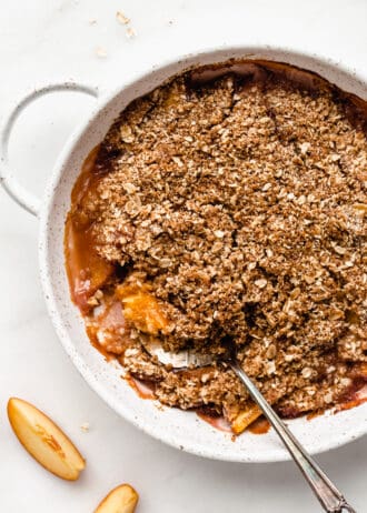 a gluten-free peach crisp in a dish with a serving spoon