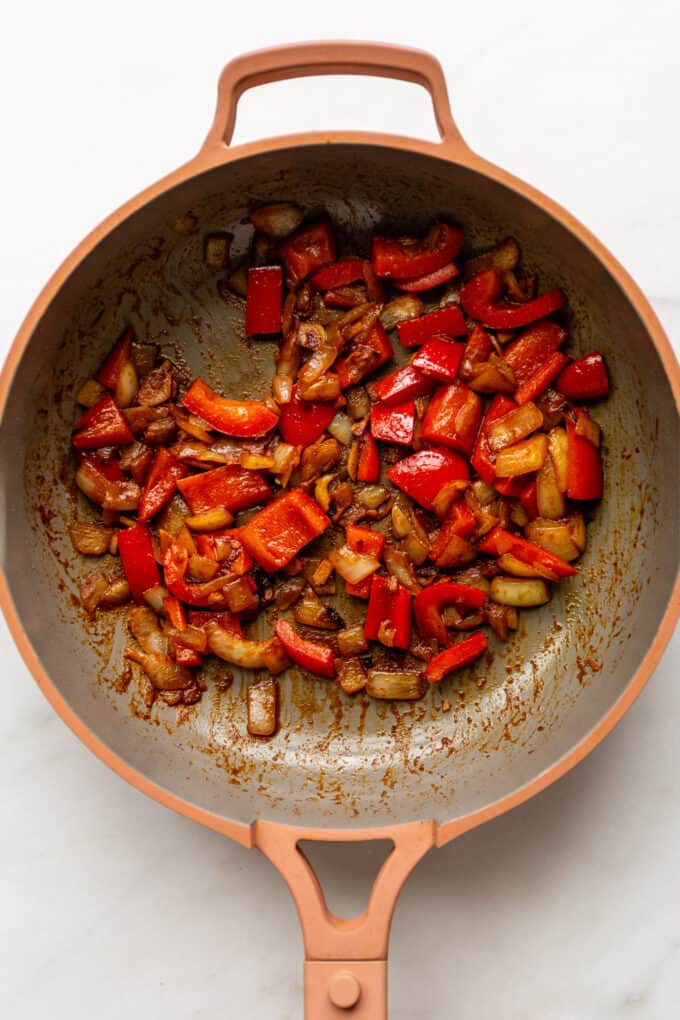 sauteéd onions and red peppers in a pink pan