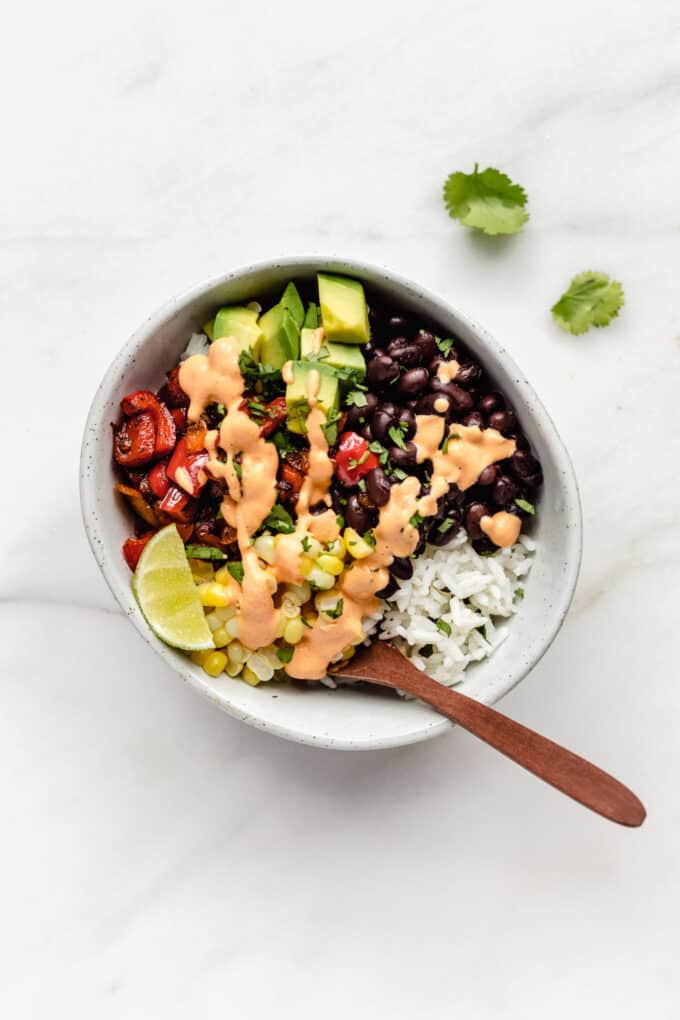 a burrito bowl with black beans, corn, avocado and peppers