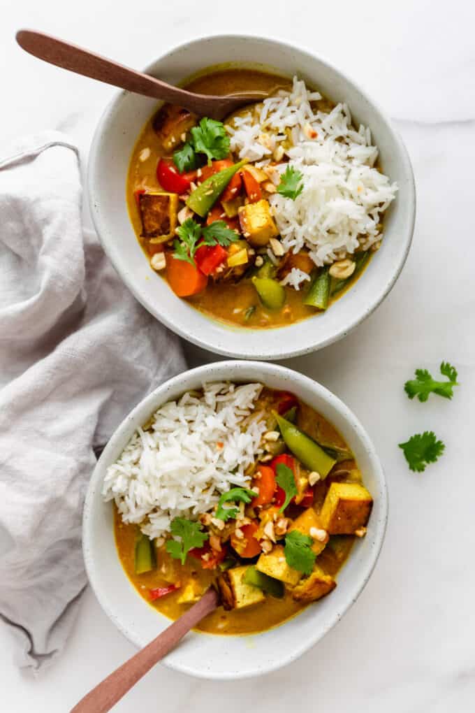two bowls of vegetable and tofu massaman curry with rice