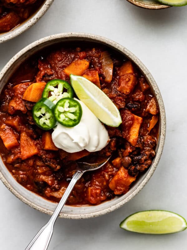 a bowl of sweet potato chili with lime, jalapeño and sour cream