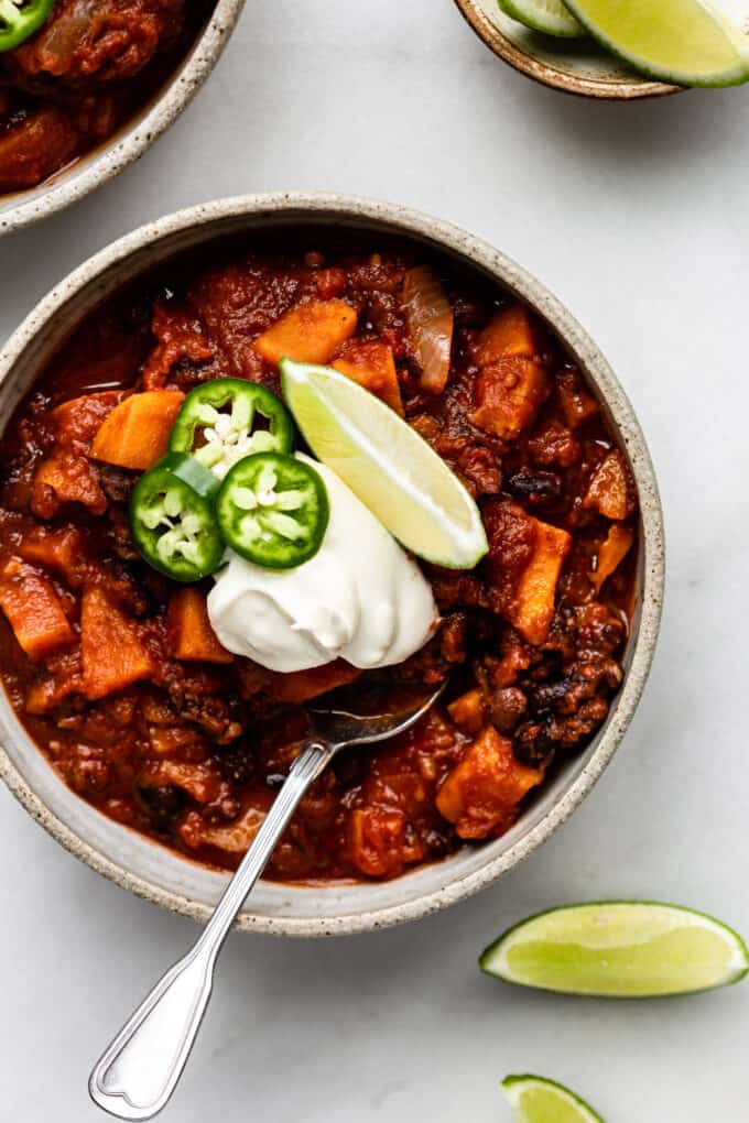 a bowl of sweet potato chili with lime, jalapeño and sour cream