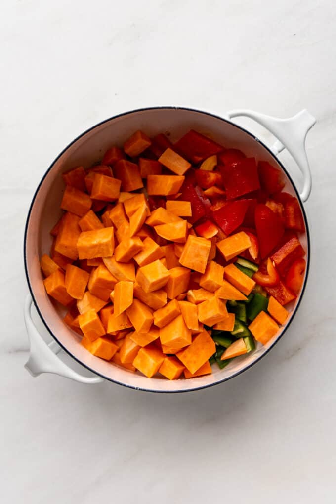 vegetables and chopped sweet potatoes in a white pot