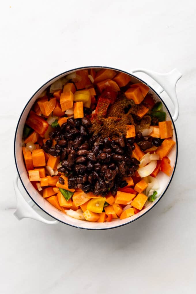 vegetables, sweet potatoes and black beans in a white pot