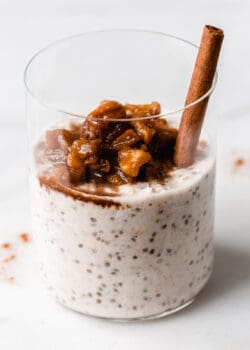 overnight oats topped with stewed apples in a white glass