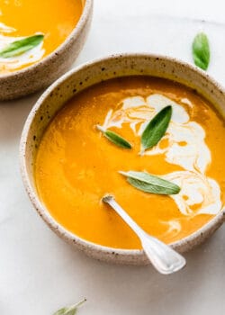 a bowl of butternut squash soup with apples with coconut milk on top