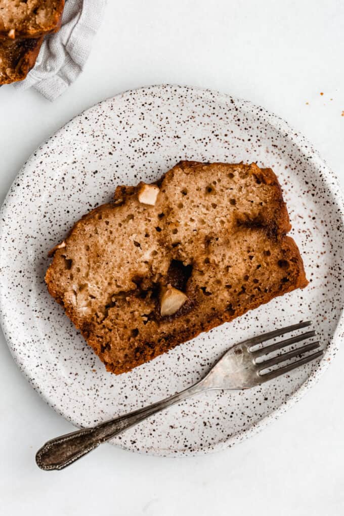 a slice of cinnamon apple bread in a white speckled plate