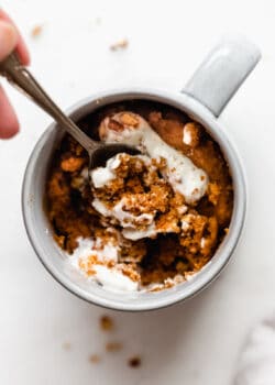 a spoon scooping pumpkin cake out of a mug