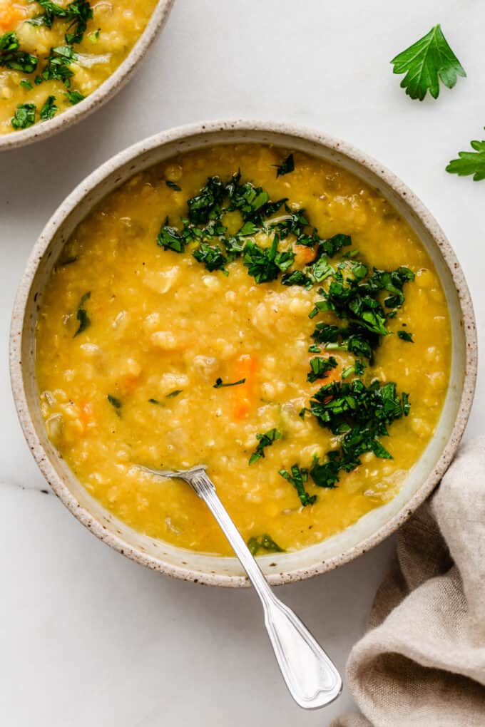 A bowl of red lentil soup topped with parsley