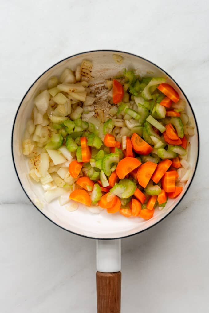 carrots, celery and onion in a white pot