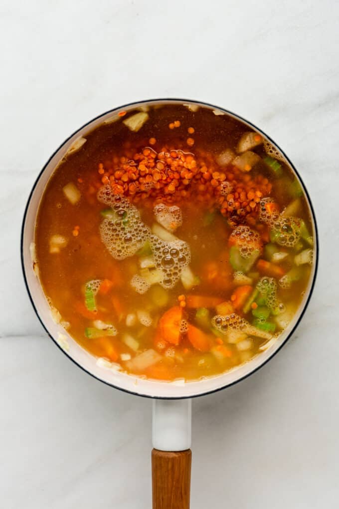 red lentils, vegetables and broth in a white pot