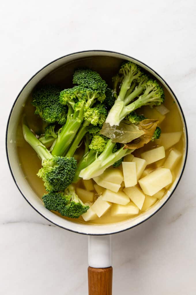 broccoli, potato, bay leaves and broth in a white pot