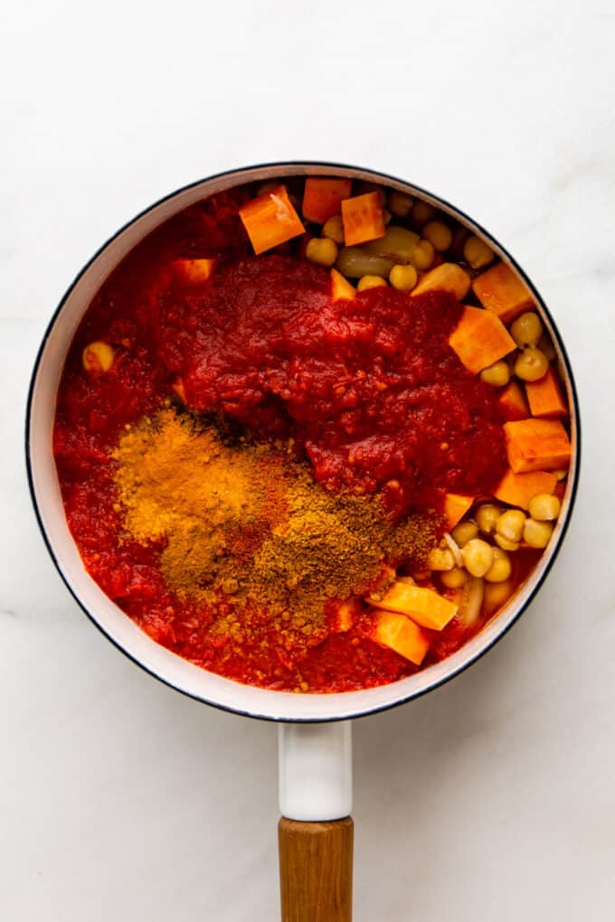 spices, crushed tomato, sweet potatoes and chickpeas in a pot