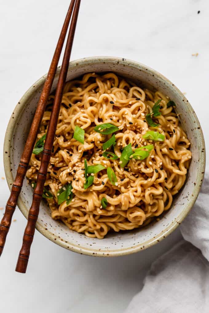 a bowl of peanut ramen noodles with chopsticks
